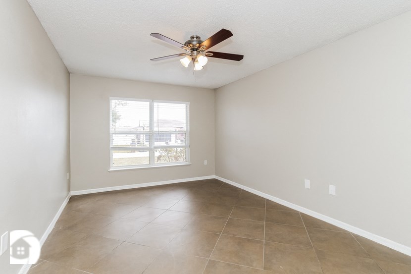 an empty living room with a ceiling fan and a window