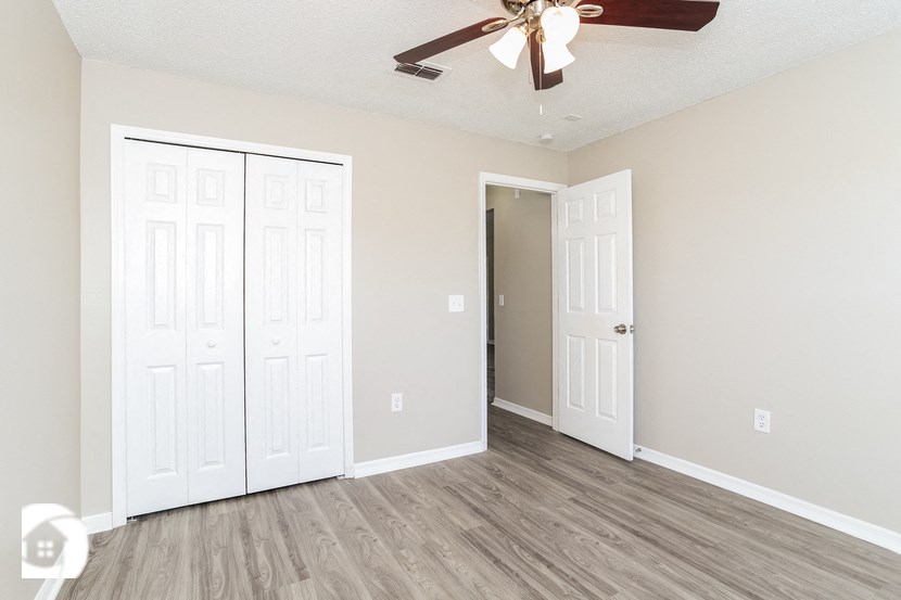an empty bedroom with two doors and a ceiling fan