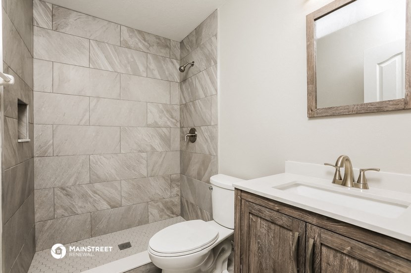 a bathroom with a toilet sink and shower and a mirror