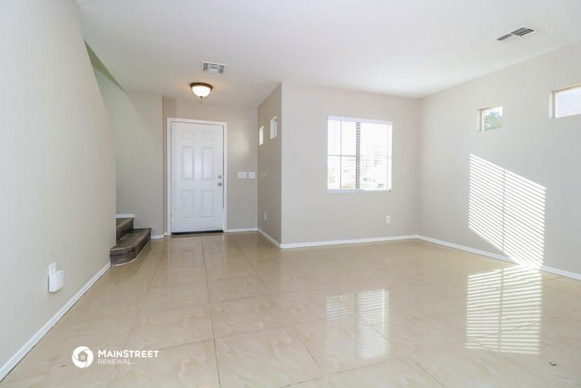 an empty living room with a white door and tiled floor