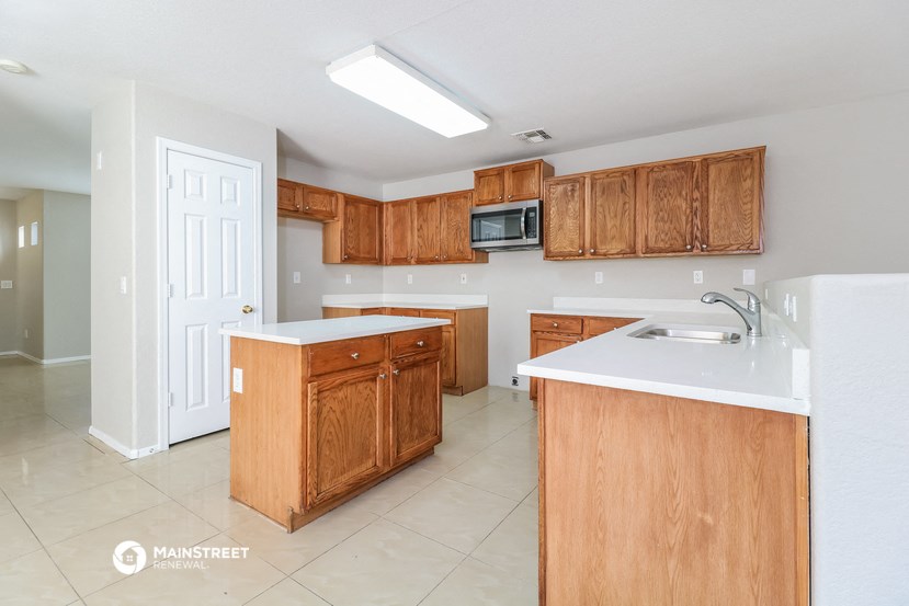 a kitchen with wooden cabinets and white counter tops and a sink