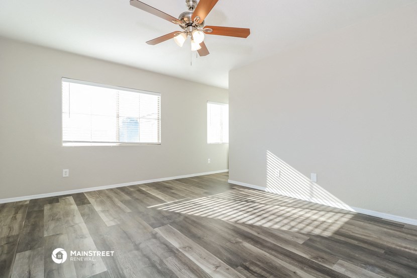 an empty living room with a ceiling fan and a window