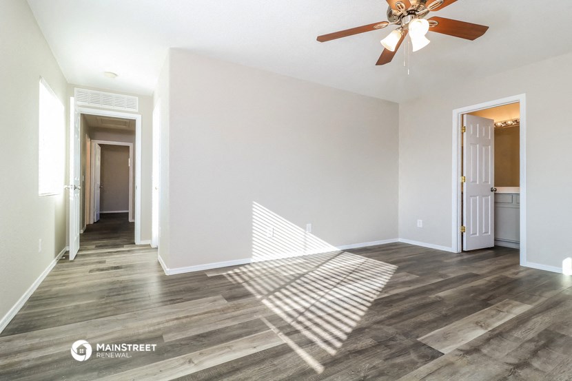 a living room with white walls and a ceiling fan