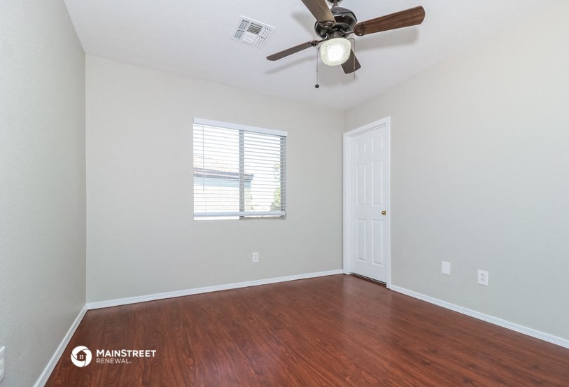 a bedroom with wood flooring and a ceiling fan