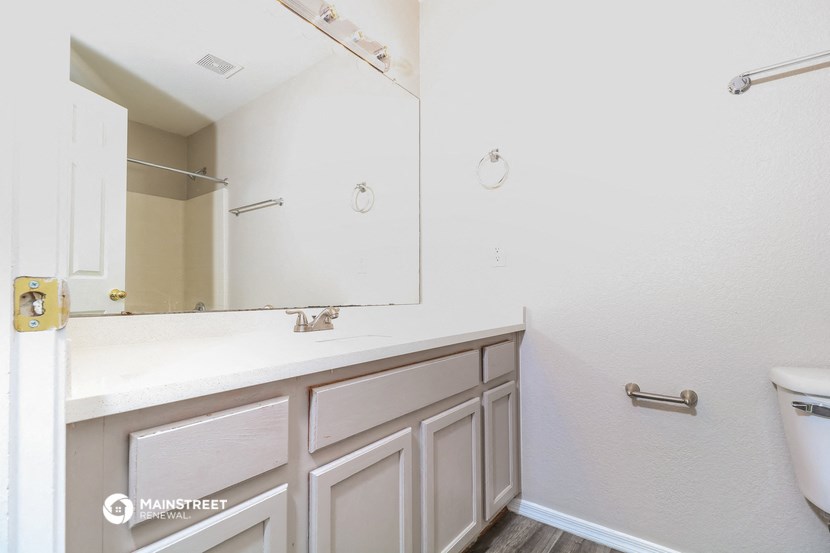a bathroom with white cabinets and a large mirror