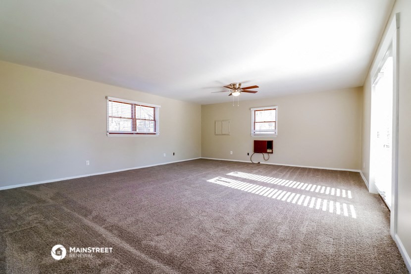an empty living room with carpet and a ceiling fan