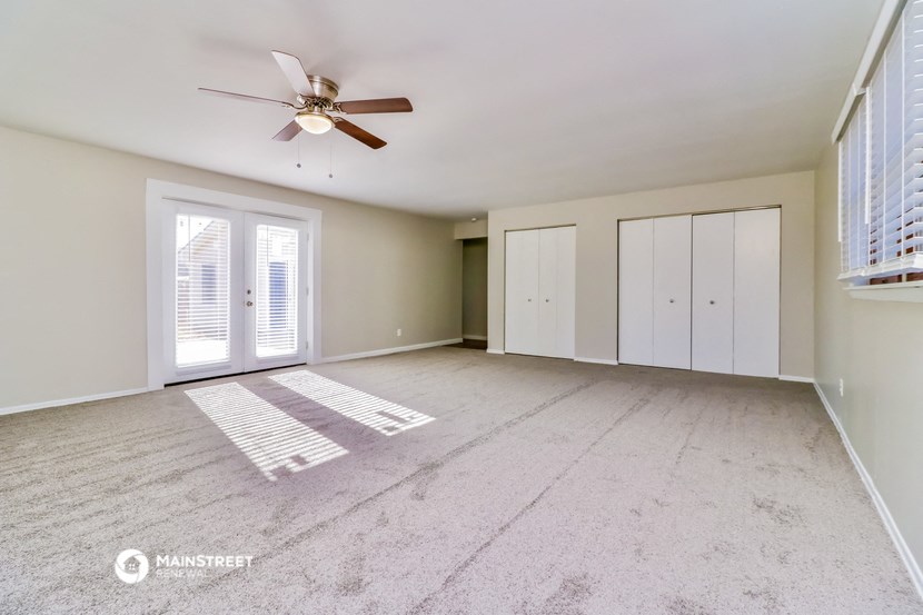 an empty living room with a ceiling fan