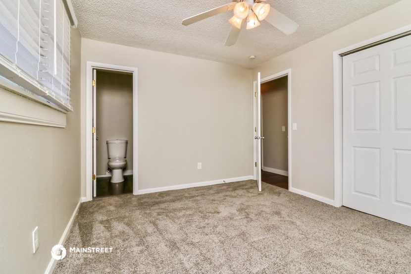 a bedroom with a ceiling fan and a door to a bathroom