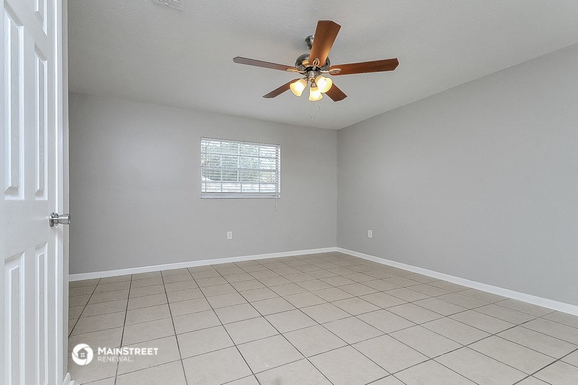 the spacious living room has a ceiling fan and a tiled floor