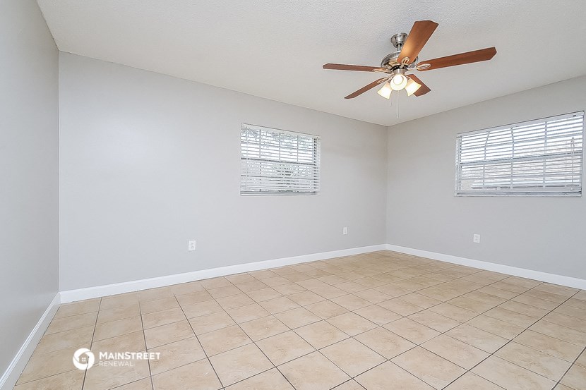 the spacious living room has a ceiling fan and a tiled floor