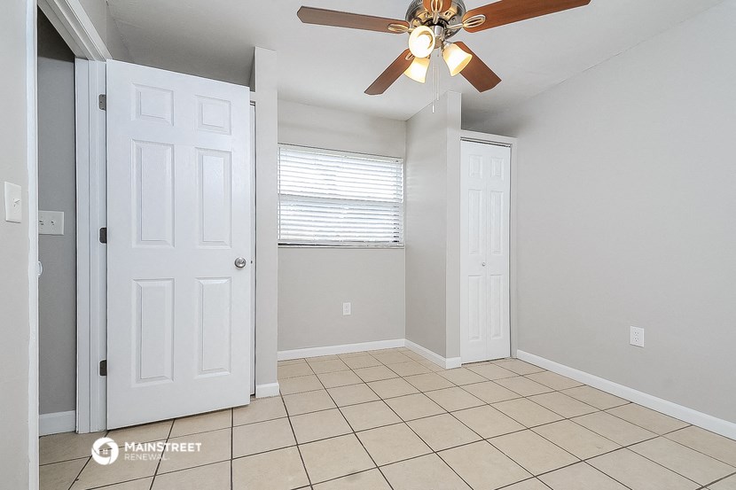 an empty room with a ceiling fan and a door to a closet