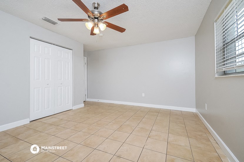 an empty living room with a ceiling fan and a tiled floor