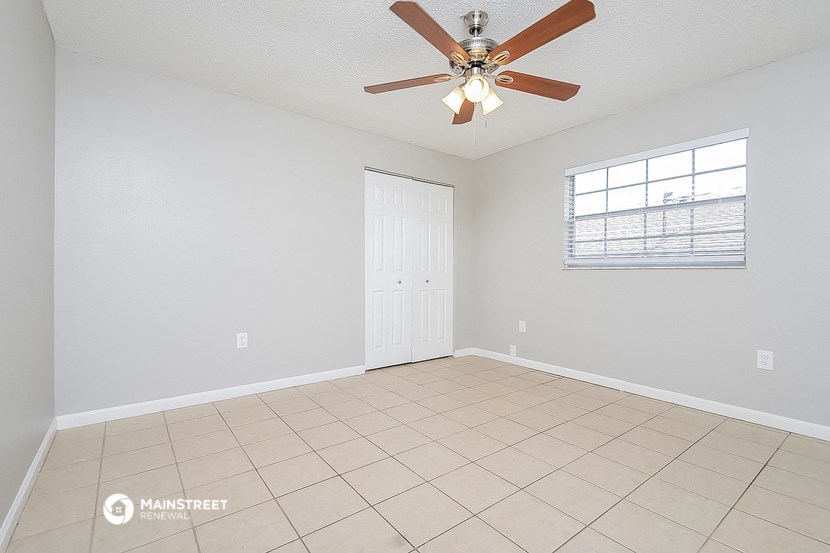 the spacious living room has a ceiling fan and a tiled floor