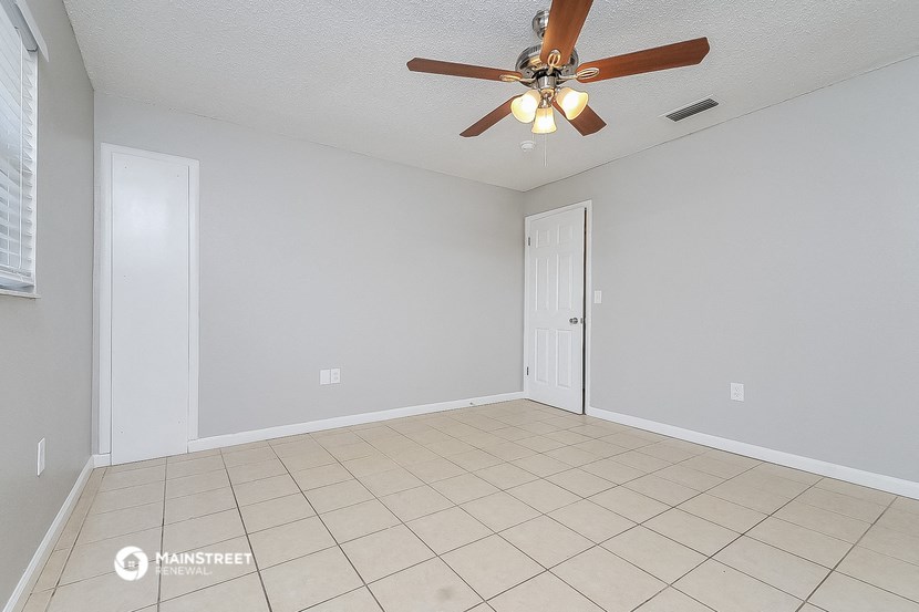 an empty living room with a ceiling fan and a tiled floor