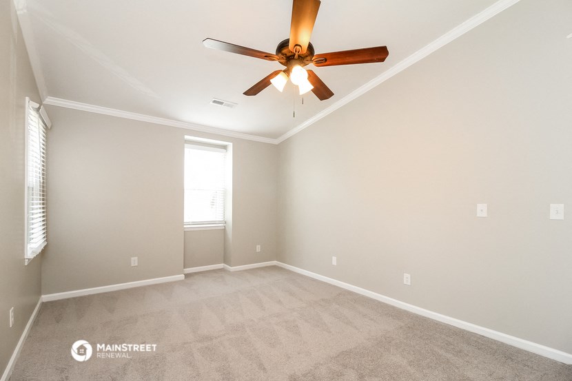 the spacious living room with ceiling fan and carpet