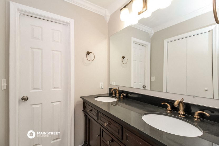 a bathroom with two sinks and a mirror and a door