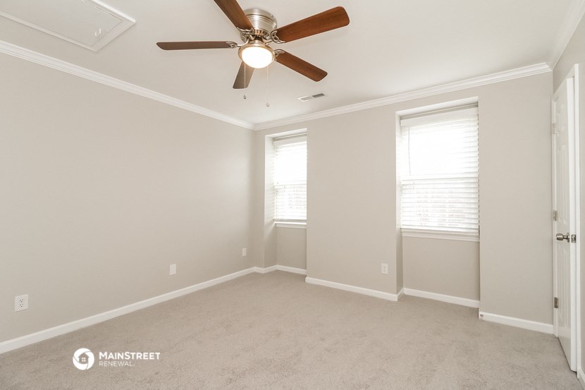 an empty room with a ceiling fan and two windows