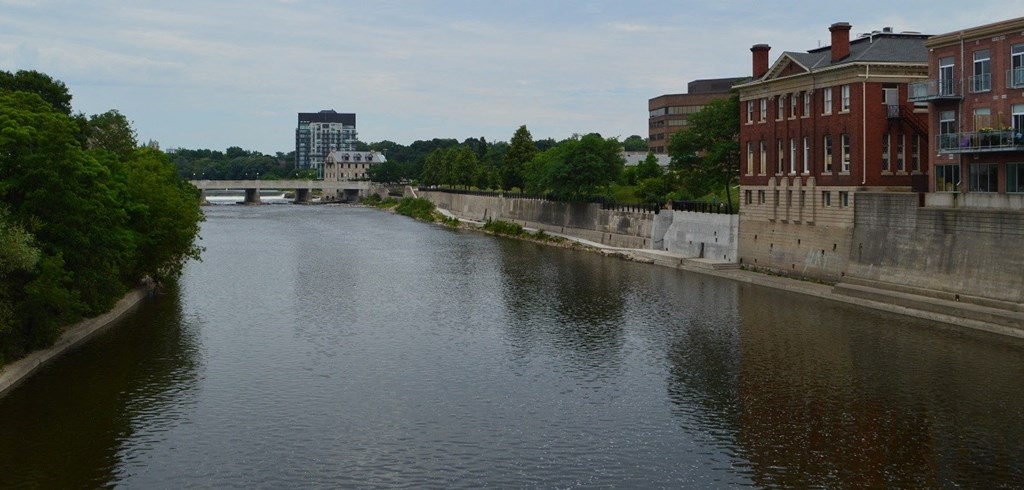 a river with buildings on either side and a bridge in the background