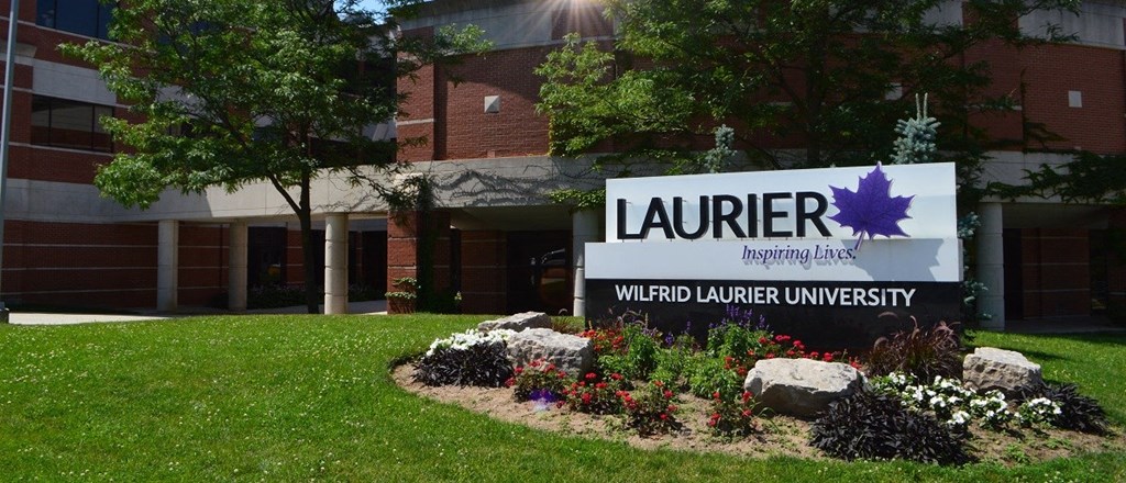 a sign in front of a building with a flower garden