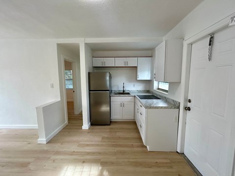 A kitchen with white cabinets and a stainless steel refrigerator.
