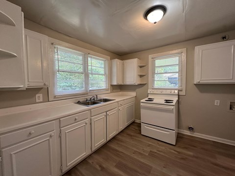 a kitchen with white cabinets and a sink and a stove