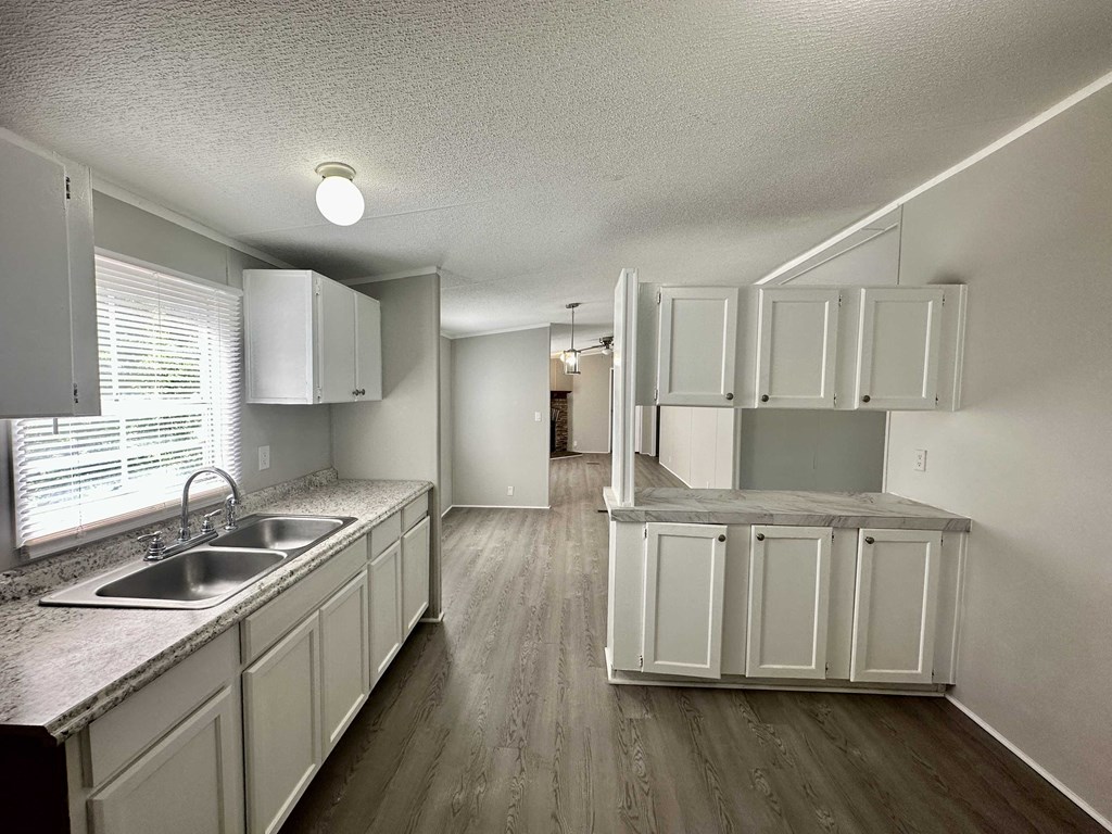an empty kitchen with white cabinets and a sink
