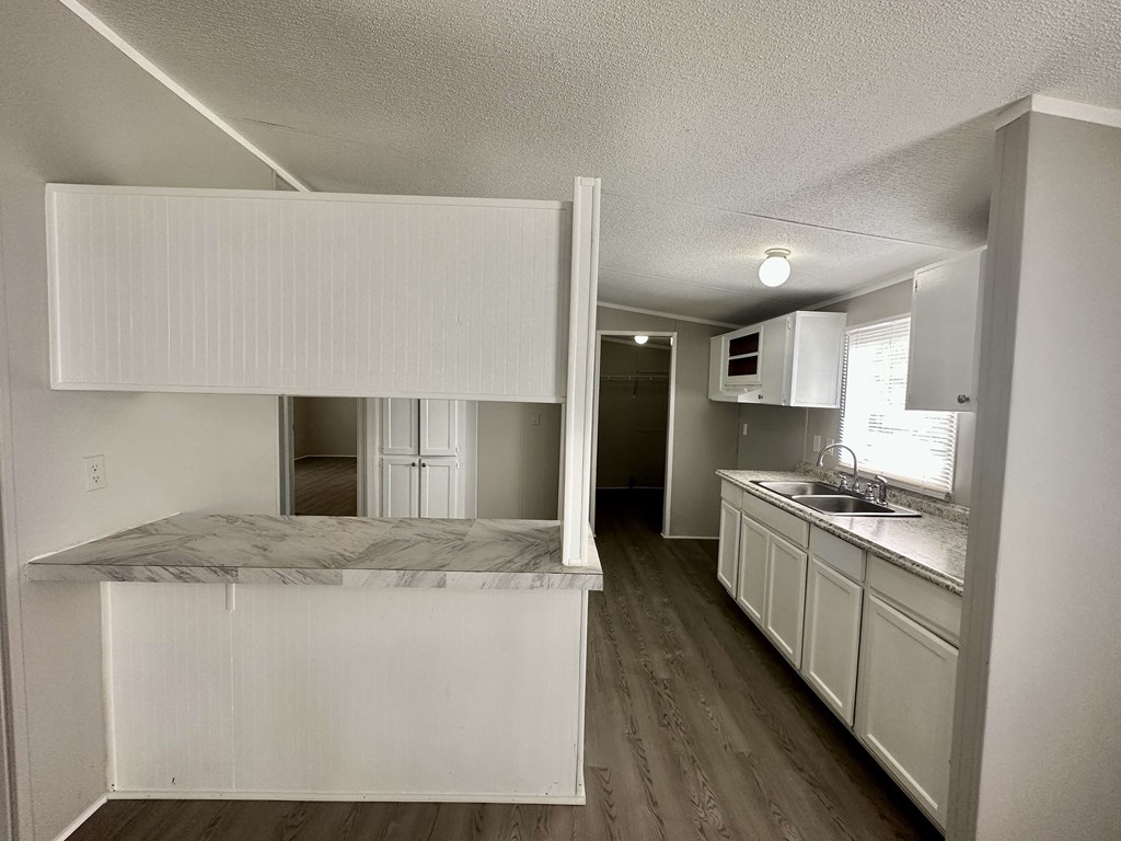 an empty kitchen with white cabinets and a counter top