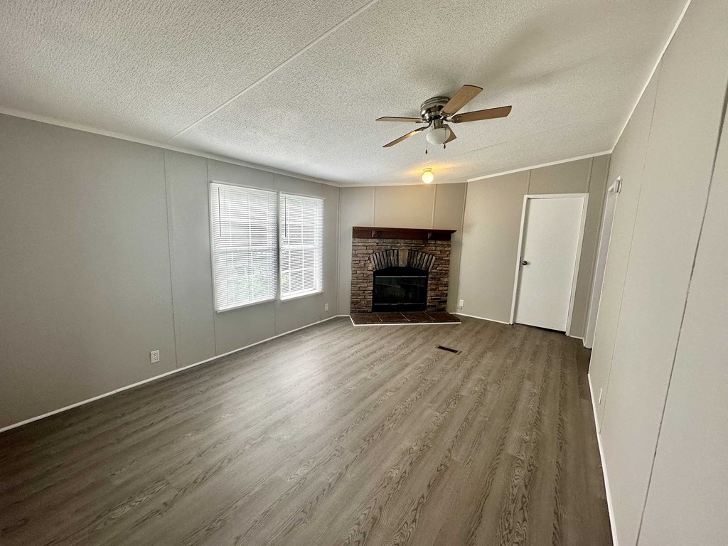 an empty living room with a ceiling fan and a fireplace