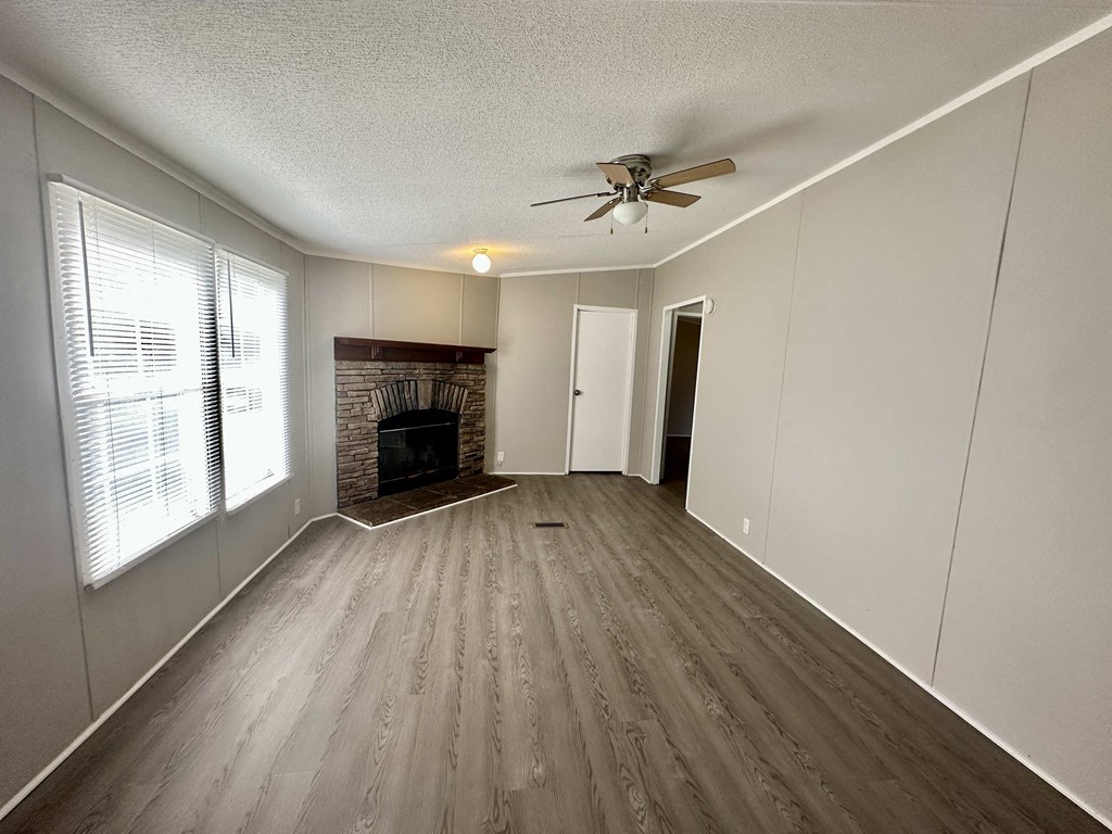 an empty living room with a fireplace and a ceiling fan