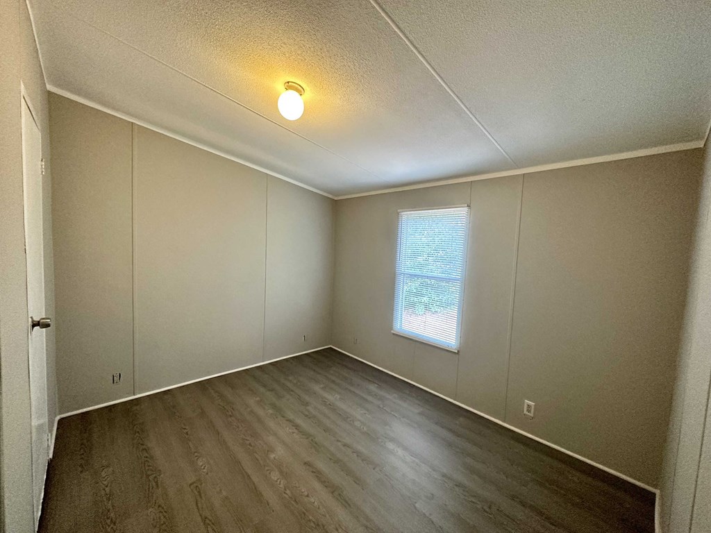 the living room of an empty house with wooden floors and a window