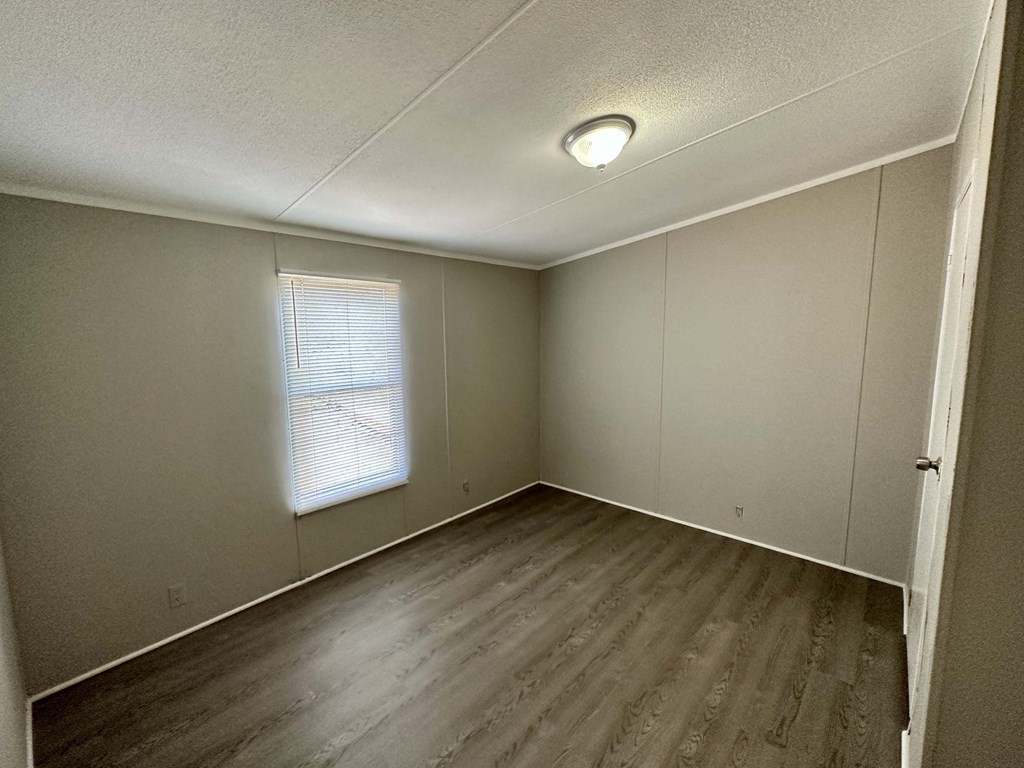 an empty room with wooden floors and a window