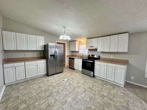 a kitchen with white cabinets and a stainless steel refrigerator