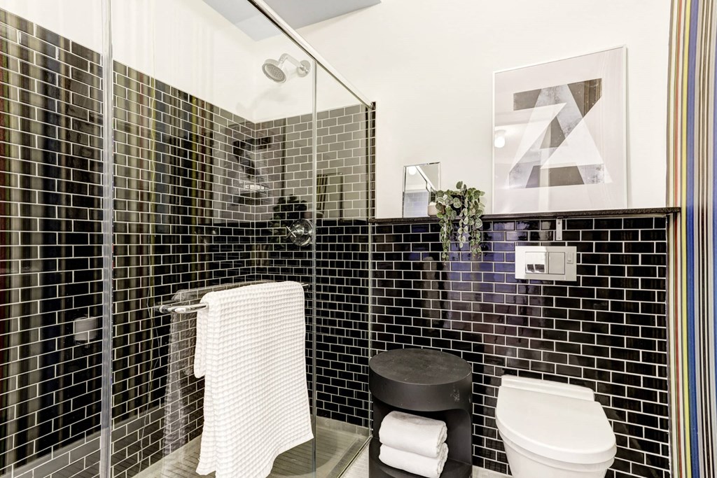 a black tiled bathroom with a toilet and a shower