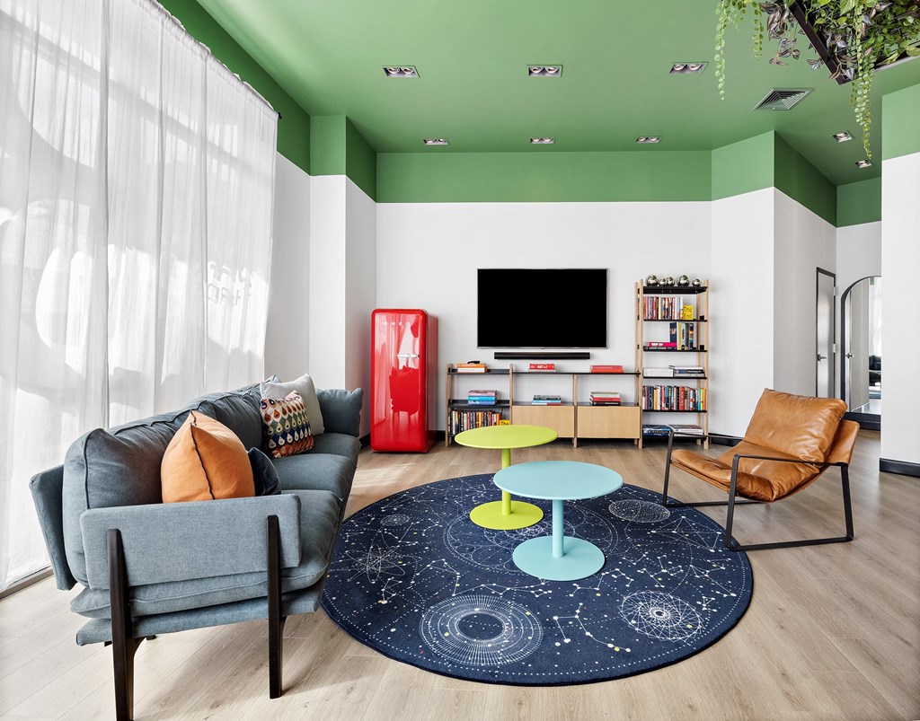 a living room with green and white walls and a blue rug
