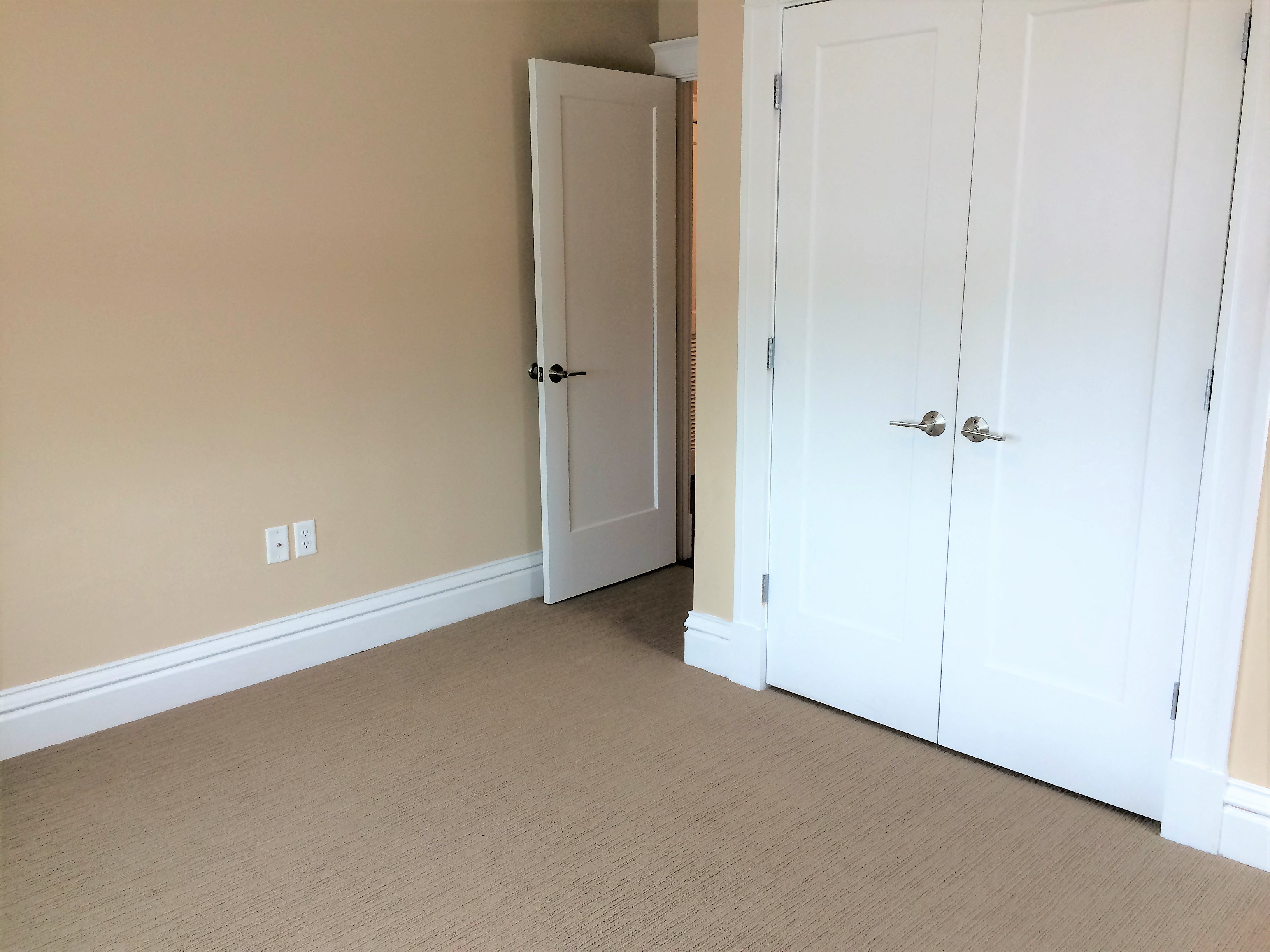 a bedroom with two closet doors and a door to a hallway