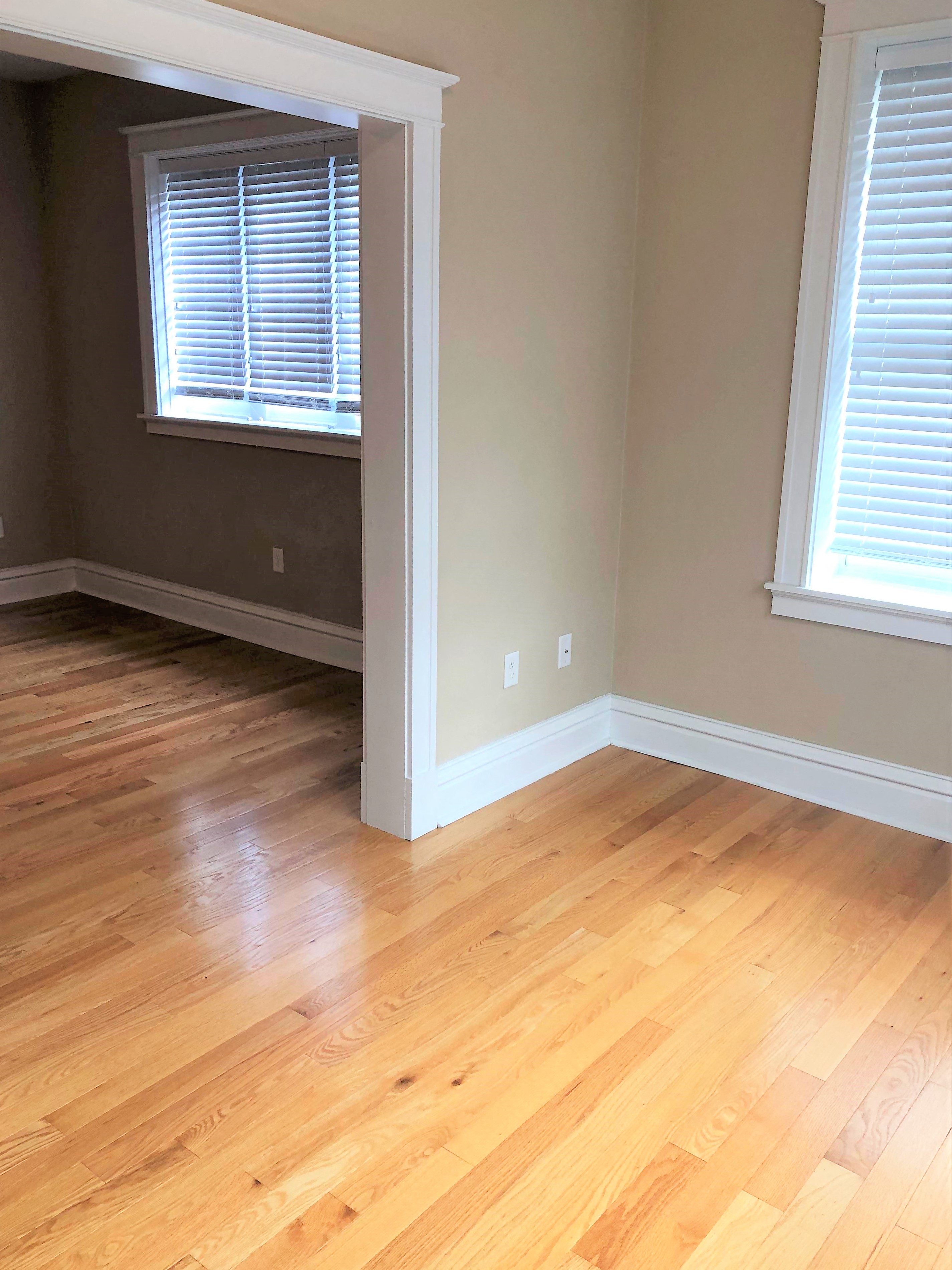 a living room with a hard wood floor and two windows