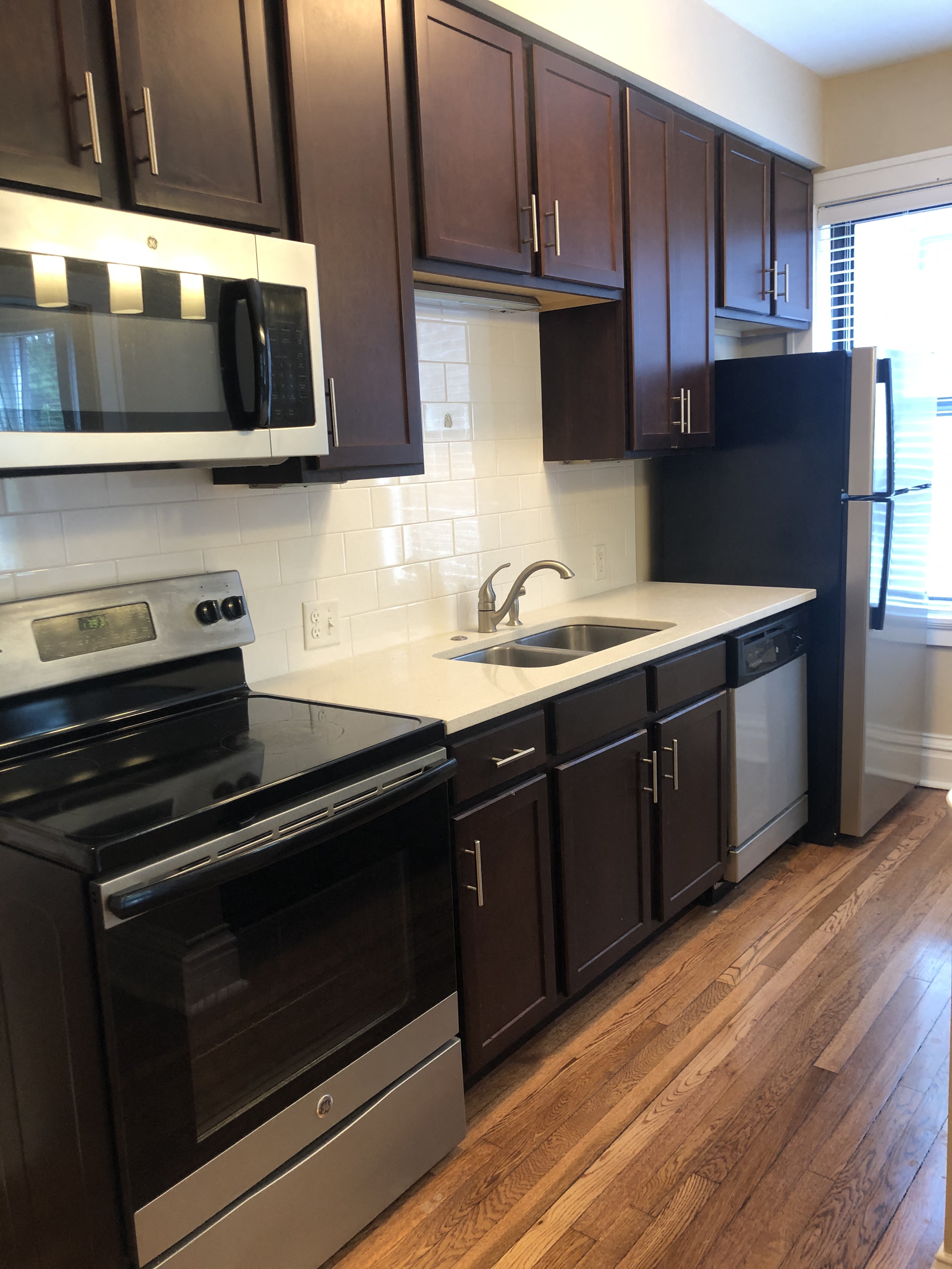 an empty kitchen with black and white appliances and wooden floors