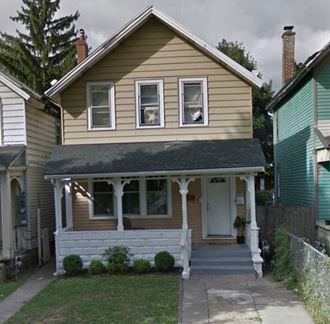a yellow house with a porch and a white door