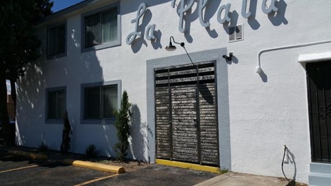 A white building with a black sign that says La Plaza.