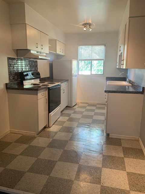 A kitchen with white appliances and a checkered floor.