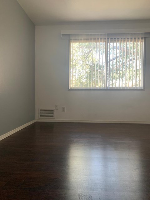 A room with a window covered by blinds and a wall heater.