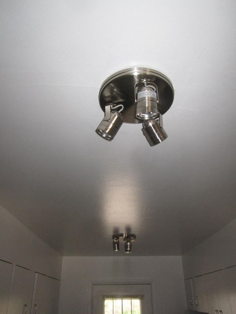 A silver ceiling light fixture with two lights is mounted on a white ceiling.