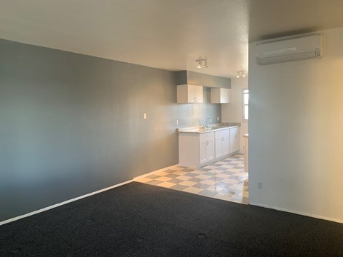 A room with a checkered floor leading to a kitchen.