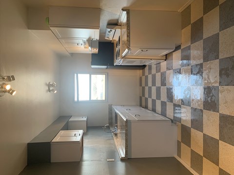 A kitchen with a checkered tile wall and a window.