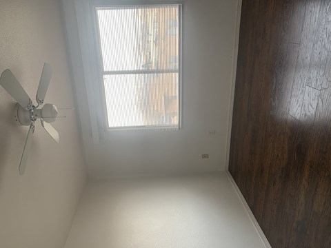 A room with a ceiling fan and a window.