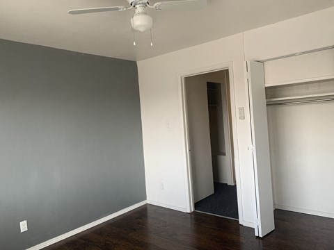 A room with a ceiling fan and a doorway leading to another room.