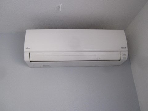 A white air conditioner is mounted on a white wall.