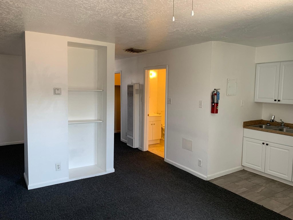 a kitchen with white cabinets and a sink and a hallway to a bathroom