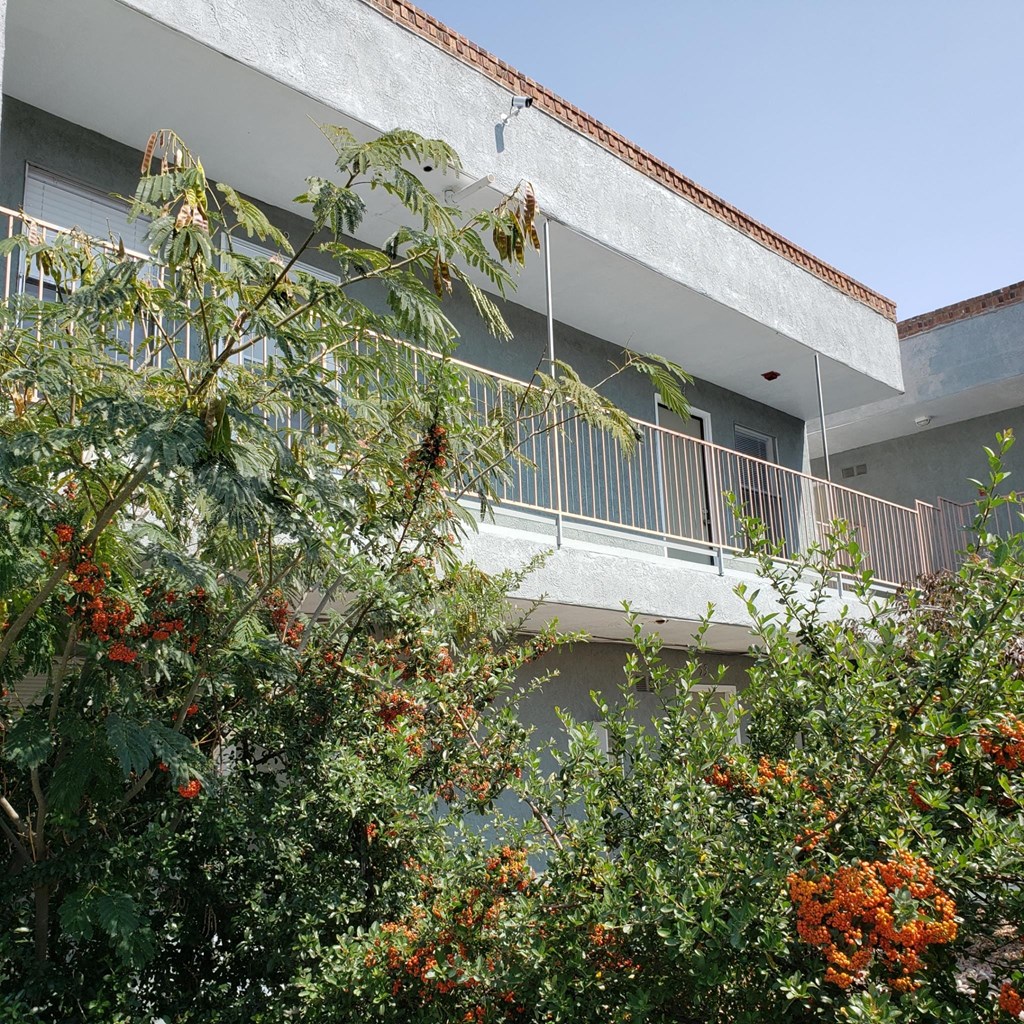 a building with a balcony and trees in front of it