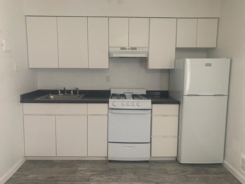 a kitchen with white cabinets and a refrigerator and a sink